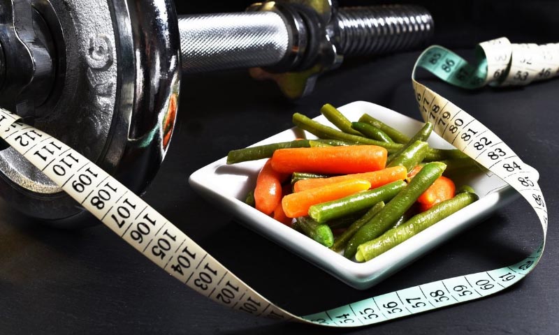 A photo of some weights, a tape measure and healthy food