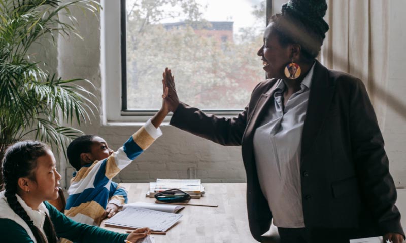 A teacher hi-fiving one of their young students